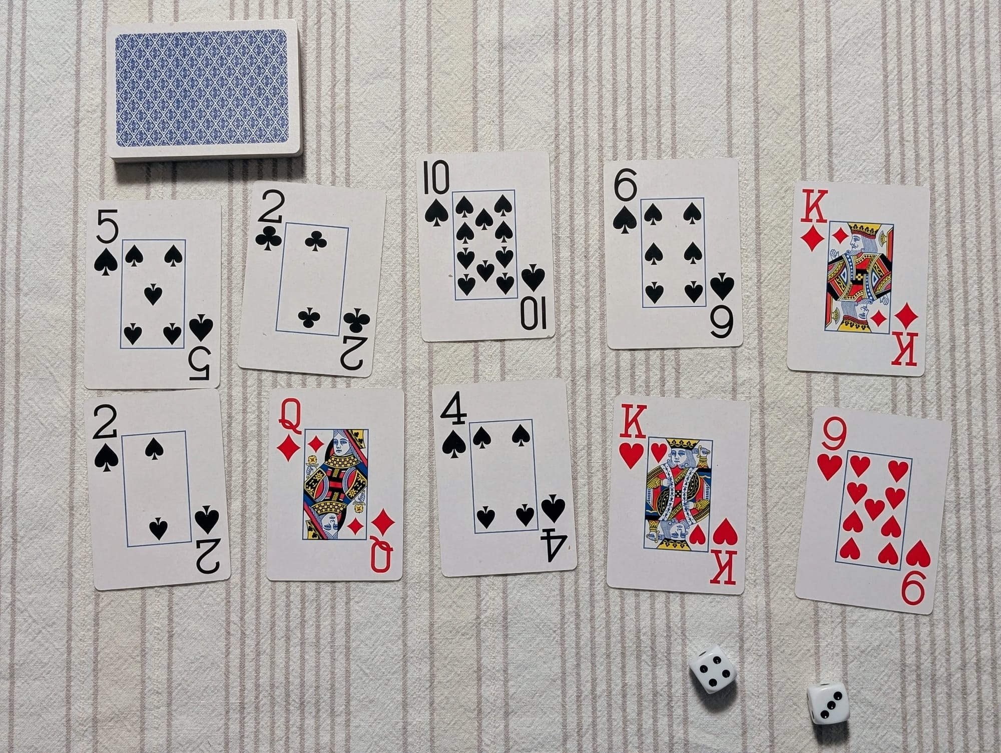 10 playing cards laying on a table with two dice.