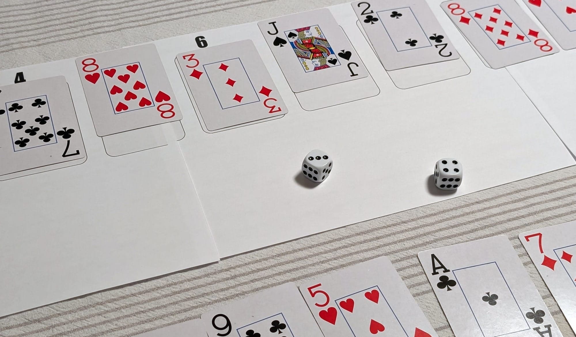 Playing cards on a printed game mat and two dice